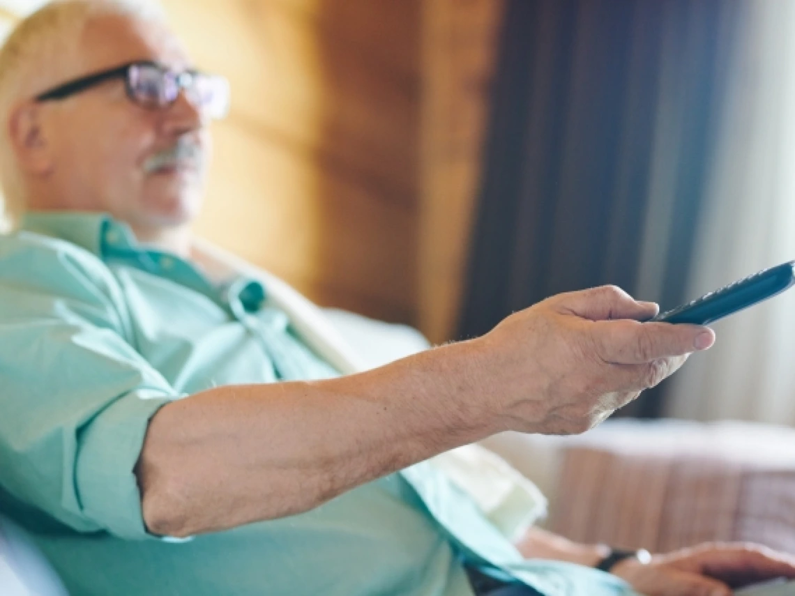 older man using a TV remote