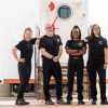 Four people posing in front of an airlock door